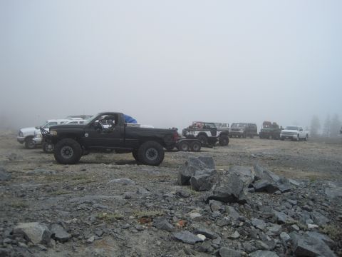1989 Ford Bronco - Several trucks and SUVs are parked in a foggy, rocky area.