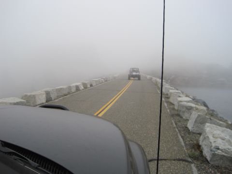 1989 Ford Bronco - Two SUVs navigate a road shrouded in heavy fog, with one vehicle visible in the distance.