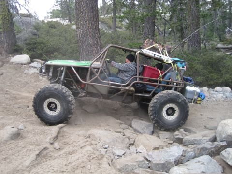 1989 Ford Bronco - A custom-built off-road buggy with a roll cage is shown traversing a challenging rocky trail.