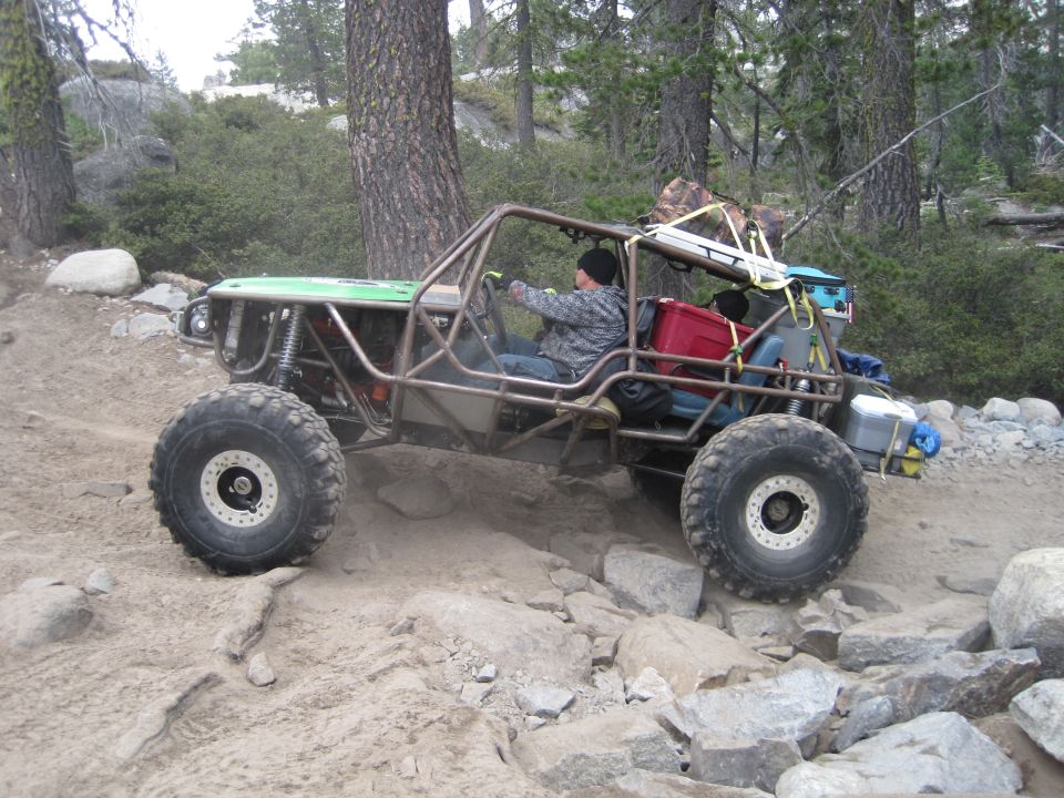 Custom off-road buggy with roll cage navigating rocky terrain