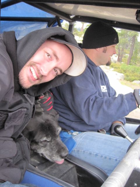 1989 Ford Bronco - Two men and a dog ride in an off-road vehicle through a wooded area.