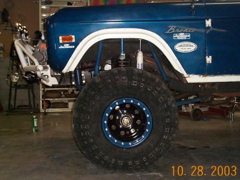 1977 Ford Bronco - A blue off-road vehicle is shown with large tires and suspension components visible.