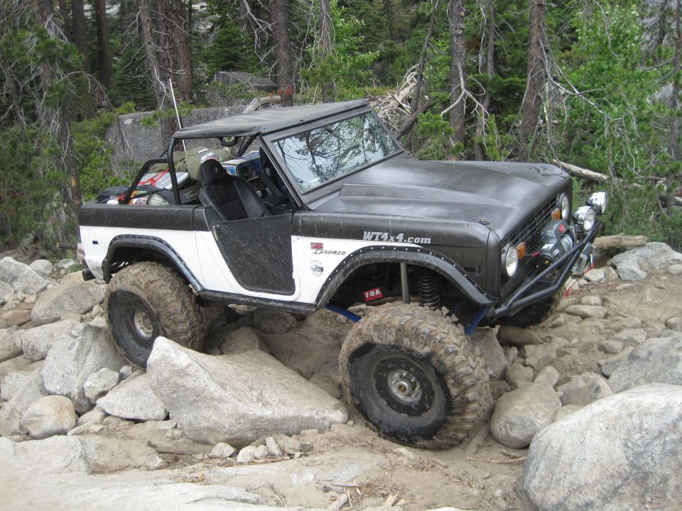 Modified Ford Bronco with large tires navigating rocky terrain. WT4x4.com sticker on fender