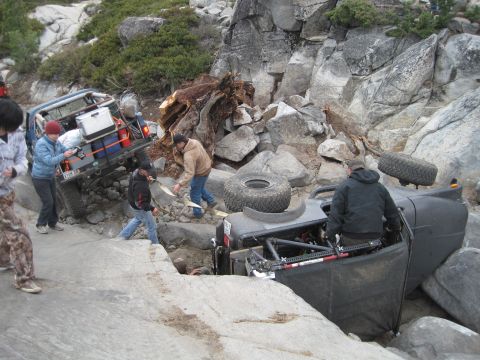 1989 Ford Bronco - Off-road vehicles struggle on a difficult rocky trail, with one vehicle overturned.