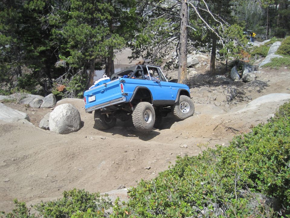 Blue Bronco off-roading on a dirt trail, lifted suspension