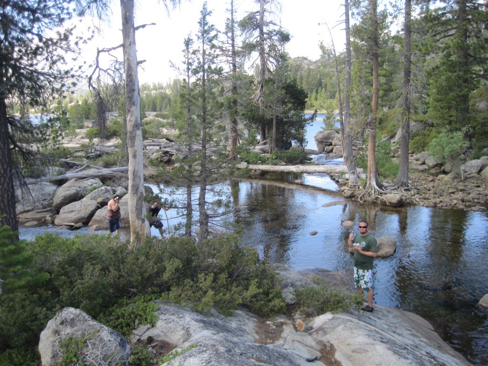 Rocky riverbank with trees and two people near water