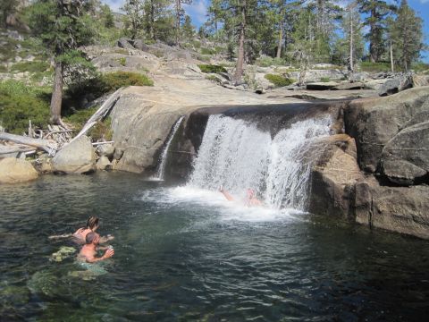 1989 Ford Bronco - People enjoy a refreshing swim at a natural waterfall in a rocky, wooded area.