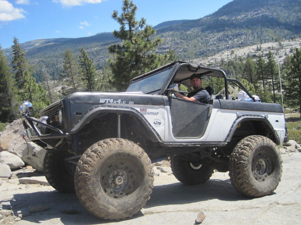 Off-road Bronco with large tires and roll cage, driver visible