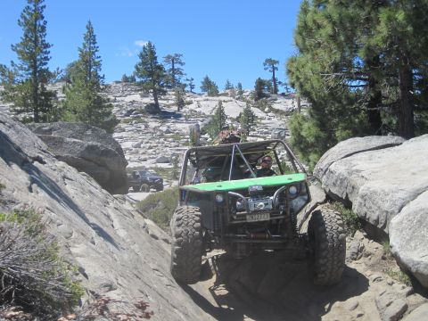1989 Ford Bronco - Two off-road vehicles navigate a challenging rocky trail under a clear blue sky.