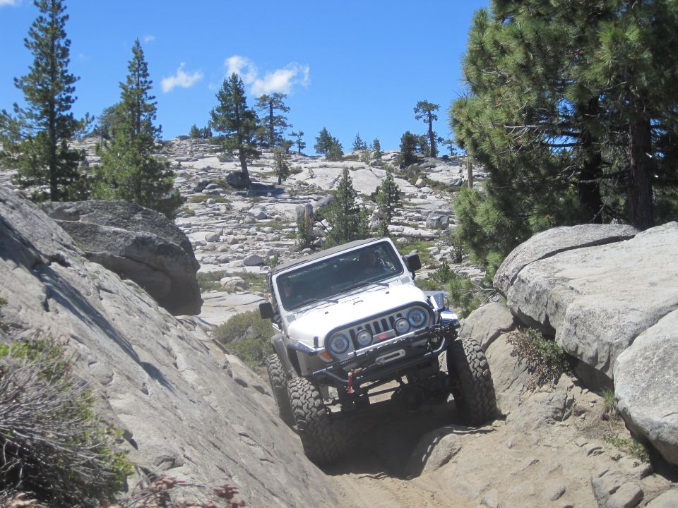 White Jeep Wrangler navigating a rocky, off-road trail