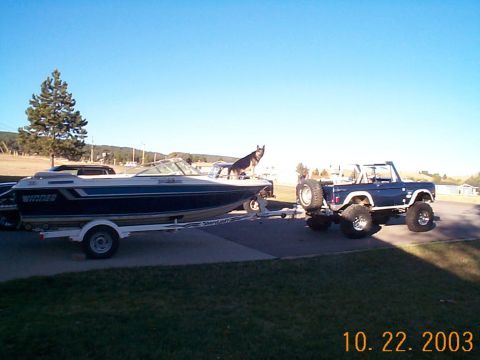 1977 Ford Bronco - A blue 1977 Ford Bronco is parked on a driveway, hitched to a boat on a trailer.