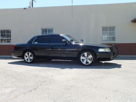 2003 Ford Crown Victoria - Profile of a black sedan showing front push bar, tinted glass and silver multi-spoke wheels