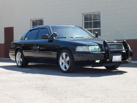2003 Ford Crown Victoria - Front quarter of a black sedan with chrome push bumper, pillar spotlight and EVIL VTC front plate