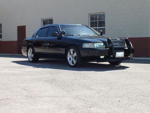 2003 Ford Crown Victoria - Black sedan front quarter showing chrome grille guard, side spotlight and EVIL VTC California plate