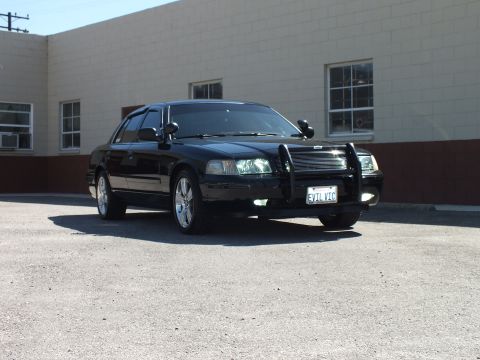 2003 Ford Crown Victoria - Front-right angle of a blacked-out Crown Victoria showing chrome wheels and push-bar bumper guard.