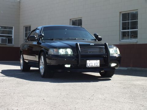 2003 Ford Crown Victoria - Front angle of a black sedan, billet grille, plate EVIL VIC framed by CROWN VICTORIA text.