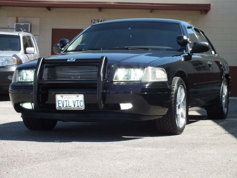 2003 Ford Crown Victoria - Low front-left angle of a black sedan, EVIL VIC plate, chrome wheels and push bar.