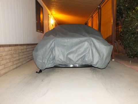 2003 Ford Crown Victoria - Front-on view of a vehicle draped in a gray fitted cover in a dim carport.