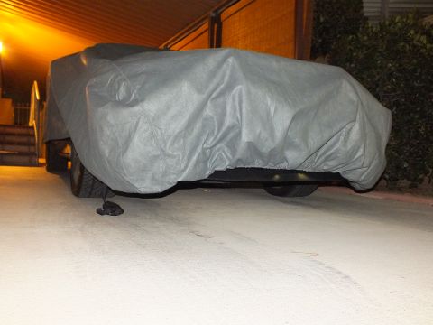 2003 Ford Crown Victoria - Rear angle of a covered vehicle showing one wheel, parked in a lit carport.