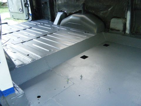 1988 Ford E350 - The interior cargo area of a van shows a freshly painted gray floor with visible metal paneling and wheel wells.