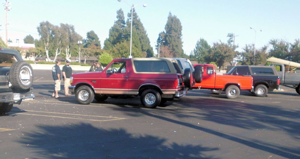 Red Ford Bronco and several pickup trucks parked in a lot