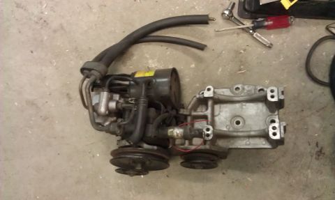 1987 Mazda RX-7 - A disassembled engine part rests on a concrete surface, with tools scattered nearby.