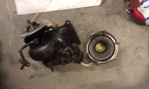 1987 Mazda RX-7 - Turbocharger and its associated housing components are shown laid out on a concrete floor.