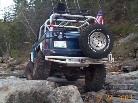 1977 Ford Bronco - Modified SUV navigating a rocky trail, an American flag on the rear.