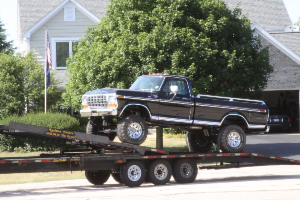 Black lifted 1970s Ford F-series pickup loaded on a tilt car trailer