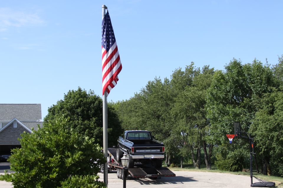 Black 1979 Ford F-250 pickup truck on a trailer, viewed from the rear