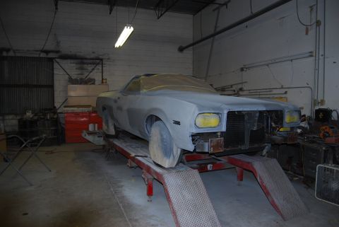 1975 Ford Ranchero - A 1975 Ford Ranchero in primer sits on a lift in a garage, ready for bodywork.
