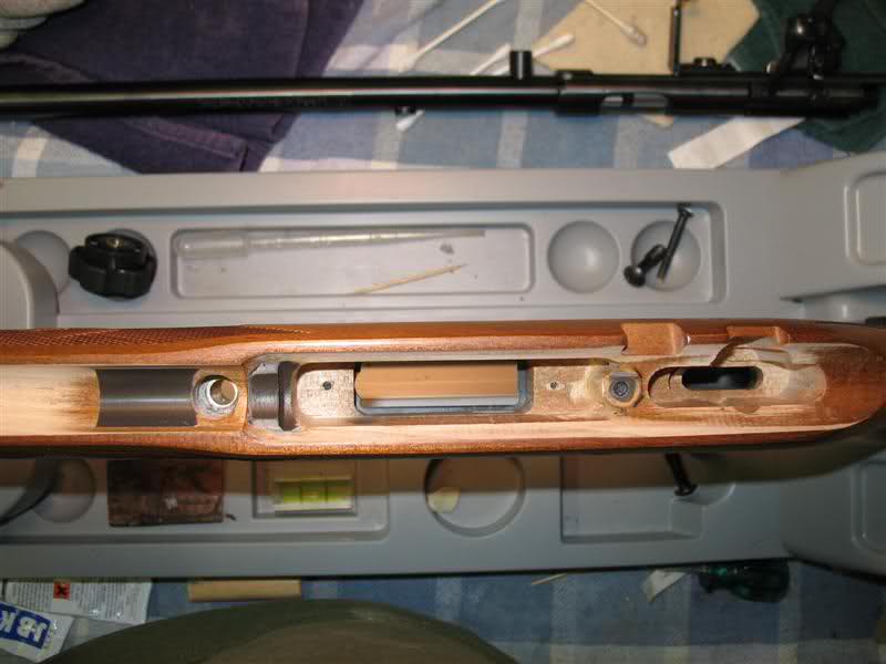 Rifle action and barrel disassembled on a workbench with tools and cleaning supplies