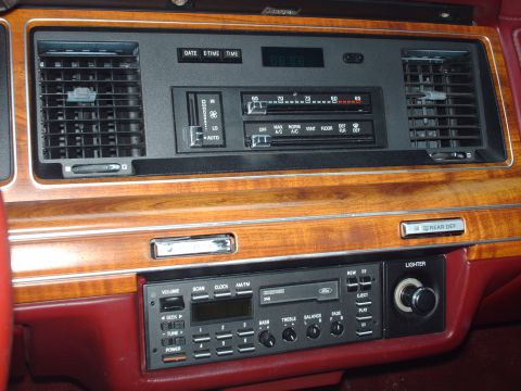 1991 Mercury Grand Marquis - Close-up of a car's dashboard wood grain accents and the center console controls.