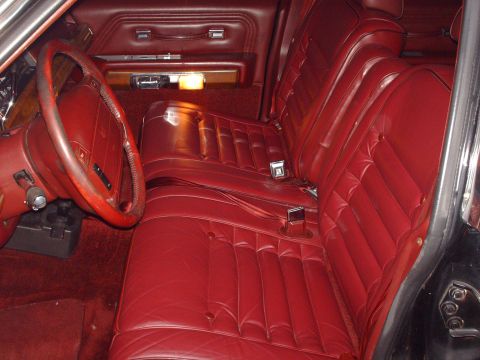 1991 Mercury Grand Marquis - The plush red leather interior of a 1991 Mercury Grand Marquis features bench seating and a classic steering wheel.