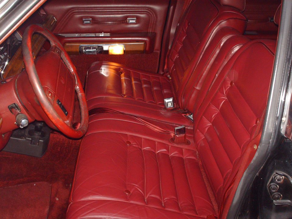 Red leather interior of a 1991 Mercury Grand Marquis with bench seats and steering wheel