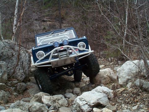 1977 Ford Bronco - This off-road SUV navigates a challenging rocky path, its body style suggesting an earlier model year than claimed.