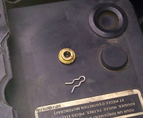 1991 Mercury Grand Marquis - A brass grommet and a metal clip are shown on a black plastic surface with some text visible.
