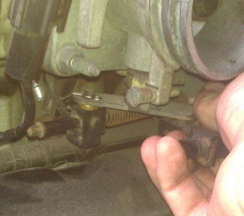 1991 Mercury Grand Marquis - A hand is shown adjusting the throttle valve cable grommet on a vehicle's engine.