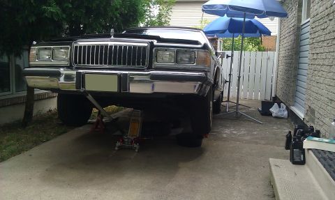 1991 Mercury Grand Marquis - Front view of a 1991 Mercury Grand Marquis being worked on, lifted by hydraulic jacks.