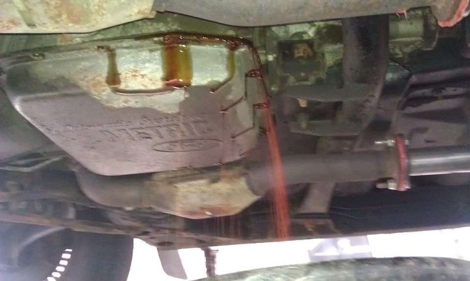 Transmission pan with fluid draining. Text on pan reads "METRIC"