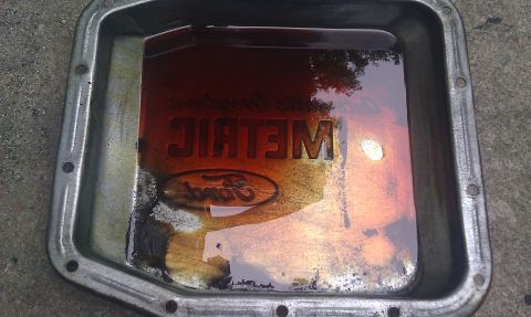 1991 Mercury Grand Marquis - A Ford transmission pan contains dark, used fluid with "METRIC" embossed on the inside.