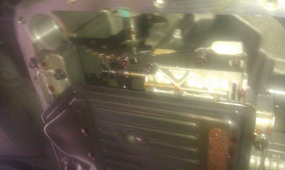 Transmission pan removed, showing valve body and some fluid. Visible internal components and bolts