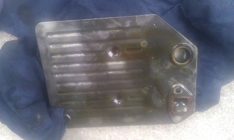 1991 Mercury Grand Marquis - A dirty transmission filter pan with visible fins and mounting holes is shown.