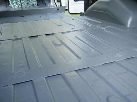 1988 Ford E350 - The interior floor of a van, showing ribbed metal panels and some inserted sections, painted gray.