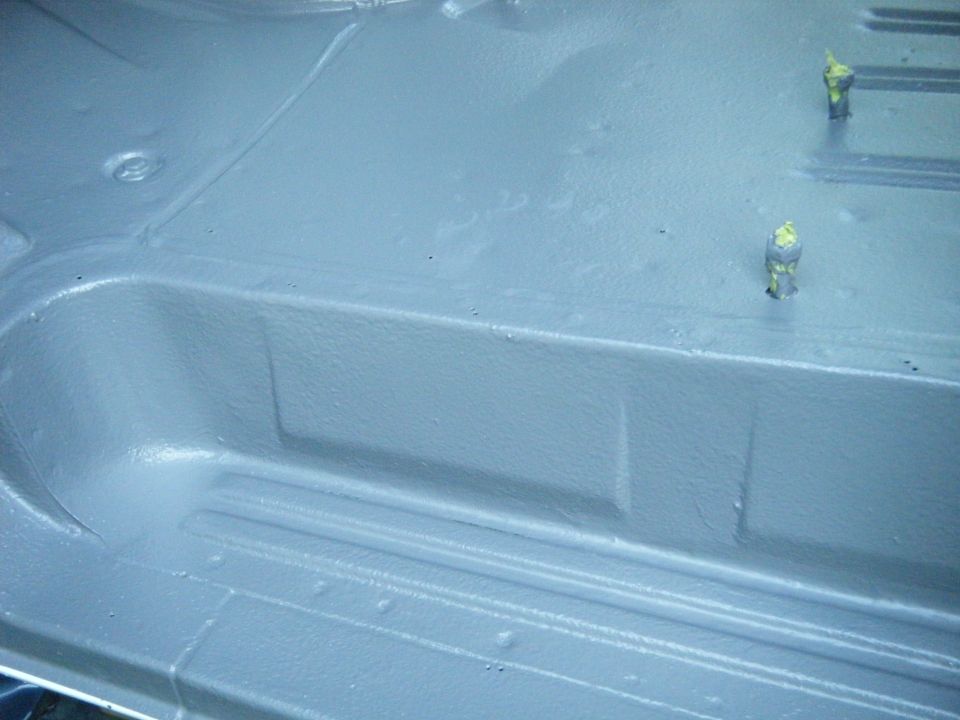1988 Ford E350 van interior floor, painted gray with some raised sections and two yellow-capped bolts