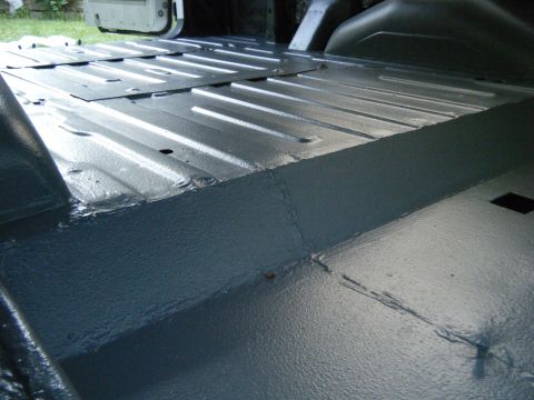 1988 Ford E350 - The interior floor of a van shows a gray painted metal surface with ribbed panels and visible seams.