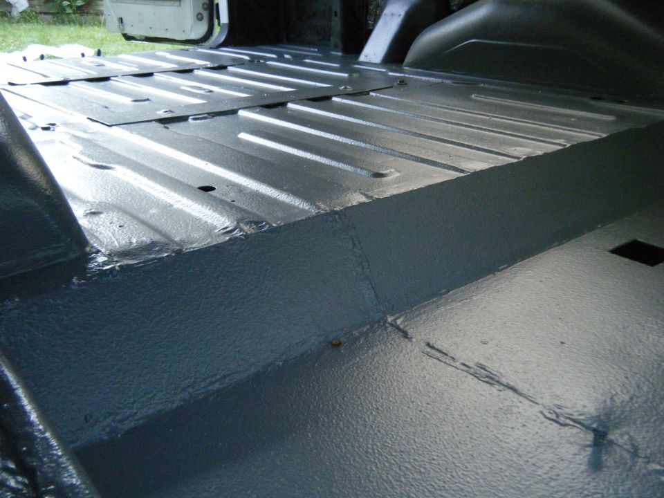 Gray painted metal floor of a van interior, showing ribbed panels and seams