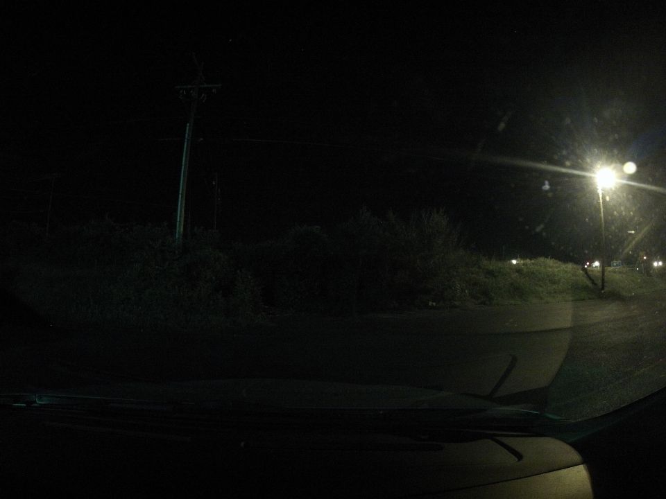 Interior view of a car at night, looking out at a dark road with streetlights