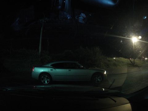 2003 Ford Taurus - A silver sedan is parked on the side of a road at night, illuminated by a street lamp.