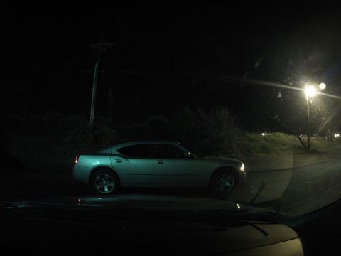 2003 Ford Taurus - A silver Dodge Charger is parked by the side of the road at night, with a street light overhead.